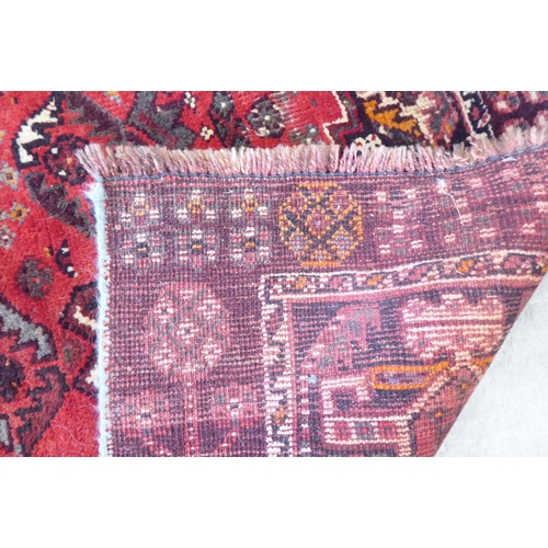 86 - A Persian Shiraz rug, decorated with repeating stylised designs, on a red ground  61