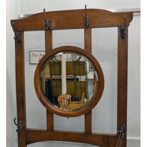 98 - An early 20thC light oak framed hall stand, comprising iron coat hooks, a vanity mirror, glove box a... 