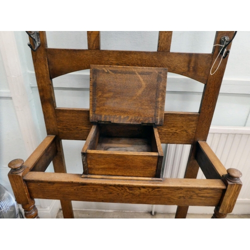 98 - An early 20thC light oak framed hall stand, comprising iron coat hooks, a vanity mirror, glove box a... 