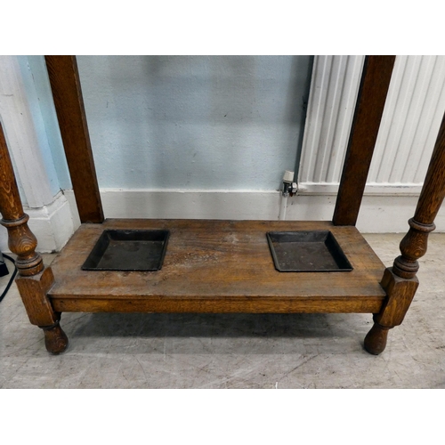 98 - An early 20thC light oak framed hall stand, comprising iron coat hooks, a vanity mirror, glove box a... 