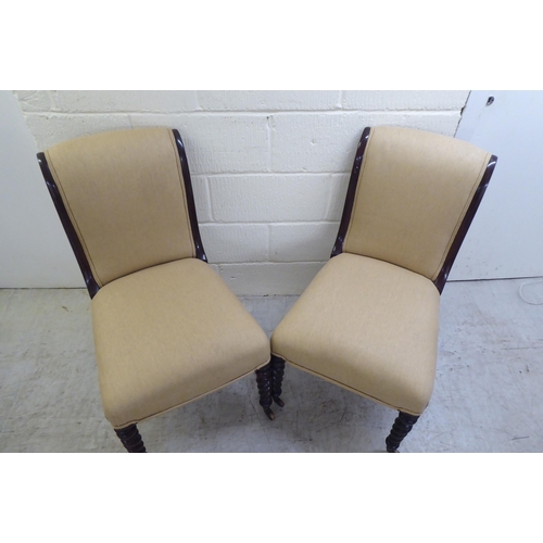 20 - A pair of early 20thC and later fabric upholstered, mahogany framed bedroom chairs, raised on barley... 