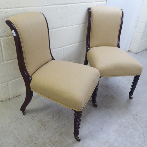 20 - A pair of early 20thC and later fabric upholstered, mahogany framed bedroom chairs, raised on barley... 