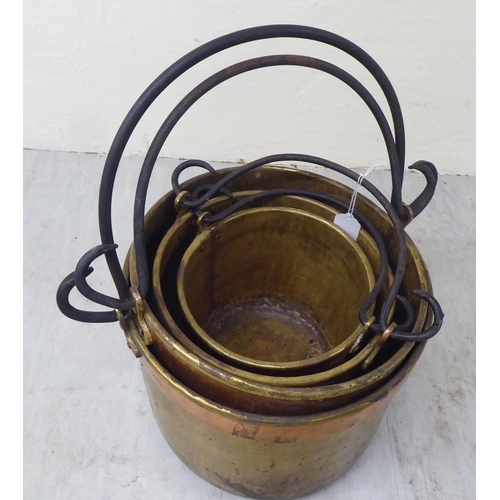 33 - A graduated set of four late 19thC brass cooking pots with wrought iron handles