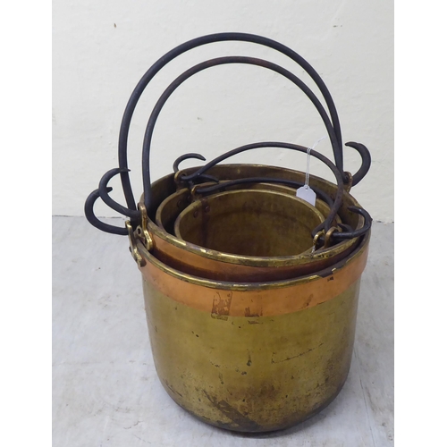 33 - A graduated set of four late 19thC brass cooking pots with wrought iron handles