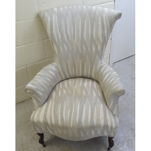 41 - A late Victorian and later fabric upholstered bedroom chair, raised on cabriole forelegs and casters