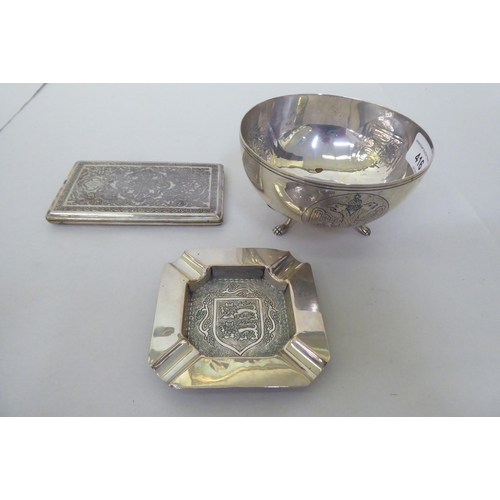 416 - White metalware, viz. an engraved, folding cigarette case; a bowl with armorial devises, raised on p... 