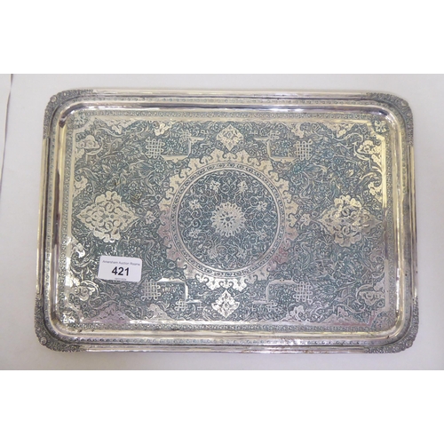 421 - A white metal dressing table tray with a raised border, allover engraved with floral and other decor... 