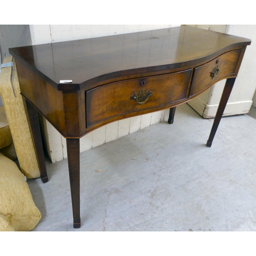 44 - A 20thC Georgian reproduction of a mahogany serpentine front, two drawer serving table, raised on sq... 