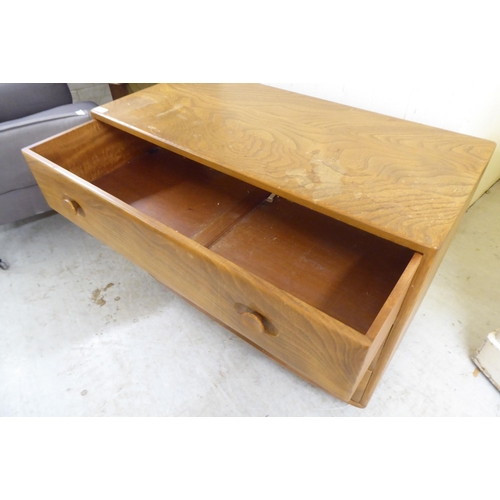 73 - An Ercol elm three drawer dressing chest, on a plinth and casters  26