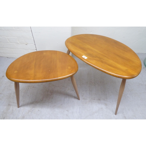 86 - A nesting set of two Ercol elm tables, raised on turned legs  largest 16