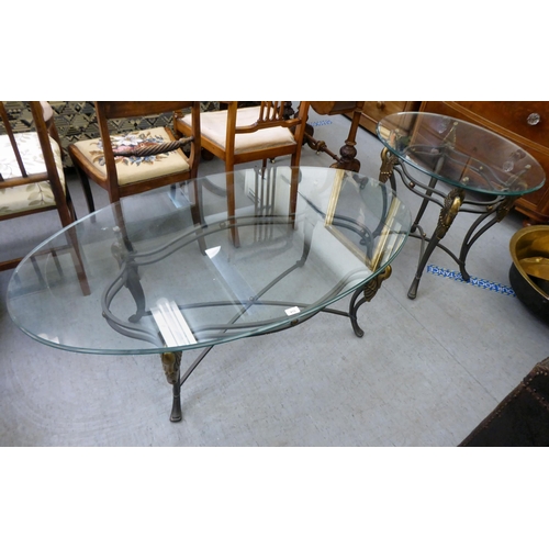 410 - A modern glass top coffee table, raised on a bi-coloured metal frame with swan and feather ornament ... 