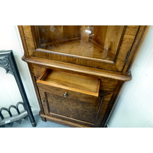 412 - A modern crossbanded walnut and oak one piece corner display unit with a glazed door, over a panelle... 