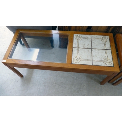 82 - A modern teak framed coffee table with a glass inset and four pottery tile top, raised on square leg... 