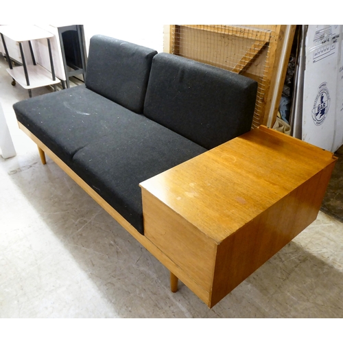 87 - A 1970s teak framed bed settee with a bar back, fabric covered cushion seat, raised on turned legs