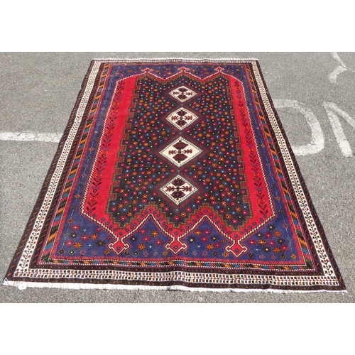 287 - A Shiraz rug, decorated with repeating flowerhead motifs, bordered by angled, coloured designs, on a... 