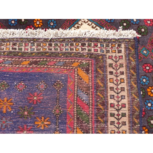 287 - A Shiraz rug, decorated with repeating flowerhead motifs, bordered by angled, coloured designs, on a... 