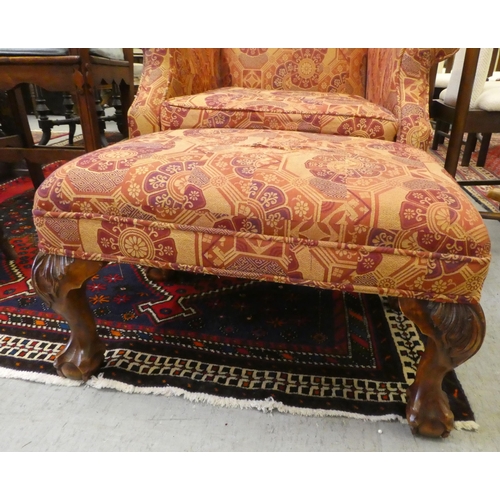 261 - A modern orange and red floral fabric upholstered wingback arm chair, raised on cabriole legs; and a... 