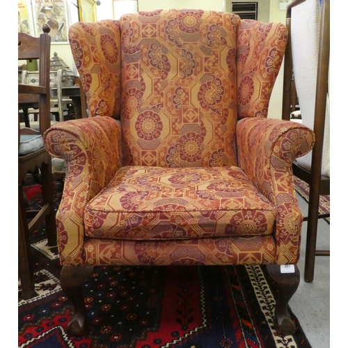 261 - A modern orange and red floral fabric upholstered wingback arm chair, raised on cabriole legs; and a... 