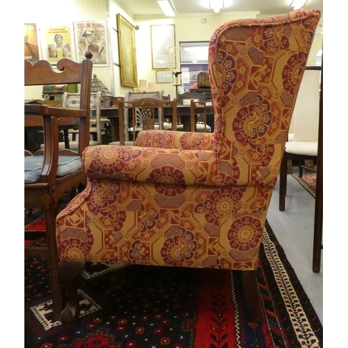 261 - A modern orange and red floral fabric upholstered wingback arm chair, raised on cabriole legs; and a... 