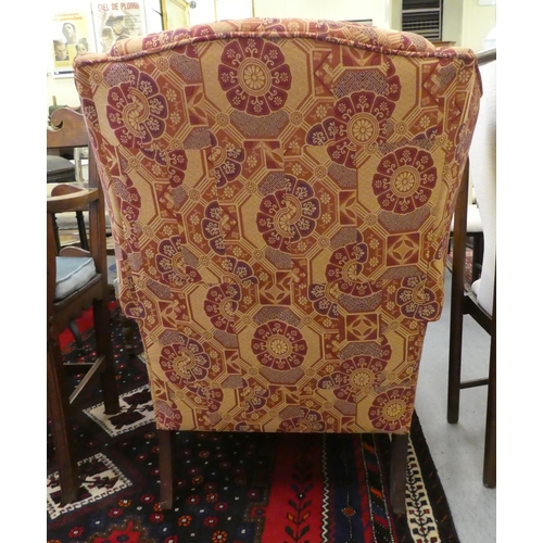 261 - A modern orange and red floral fabric upholstered wingback arm chair, raised on cabriole legs; and a... 