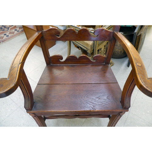 96 - A 19th/20thC country made, oak framed elbow chair with a low ladder back and open, level arms, the s... 