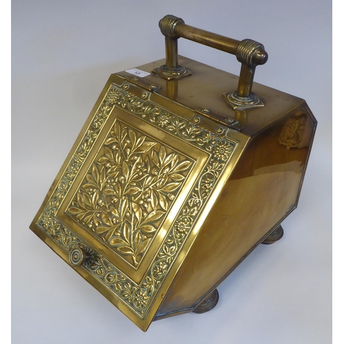 13 - A late Victorian brass coal box with an angled, hinged lid, embossed with flora and foliage