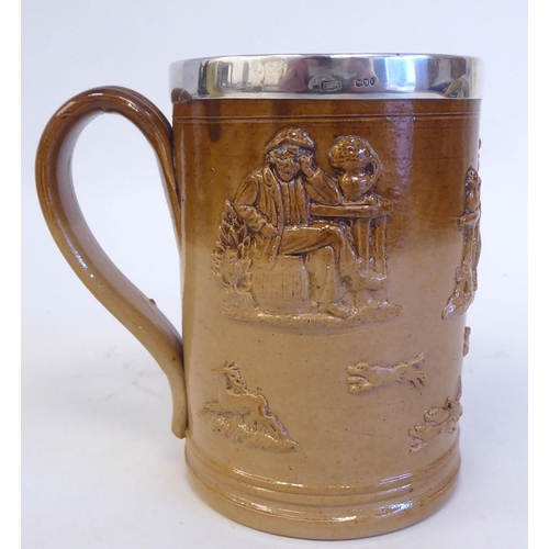 195 - A two tone brown glazed stoneware harvest mug with a loop handle and applied silver rim  maker'... 