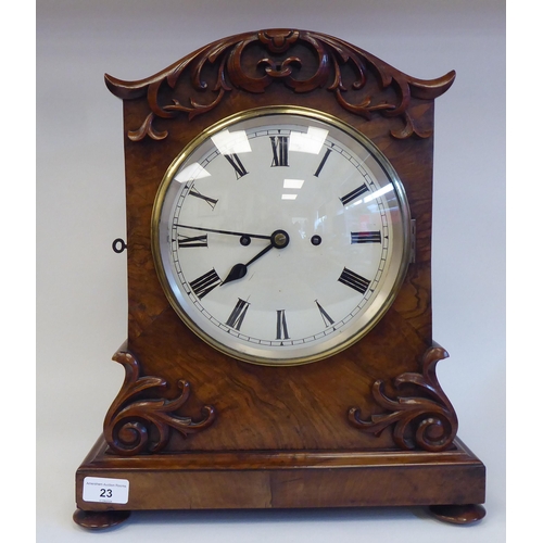 23 - A William IV walnut cased mantel clock with applied, scroll carved ornament, a round arch top, strai... 