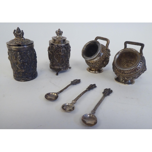 231 - A four piece Anglo-Indian white metal condiments set, cast in vignette panels with religious figures