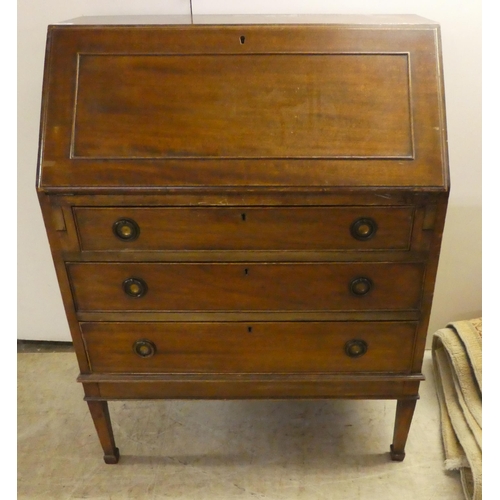 263 - An early 20thC mahogany bureau, the fall flap over three graduated drawers, raised on square, tapere... 