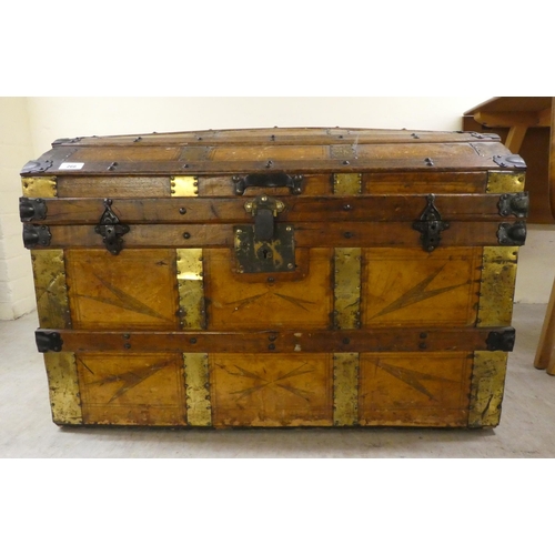 266 - An early 20thC brass and oak bound trunk with straight sides and a hinged, domed lid, on a plinth&nb... 