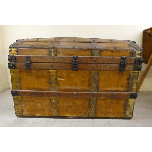 266 - An early 20thC brass and oak bound trunk with straight sides and a hinged, domed lid, on a plinth&nb... 