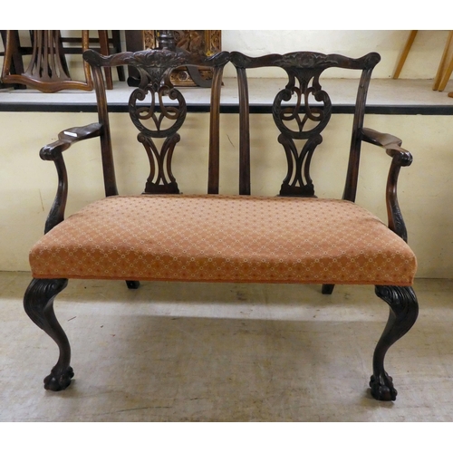 267 - An early/mid 20thC Georgian design,  mahogany twin carved, splat back, open arm two person sett... 