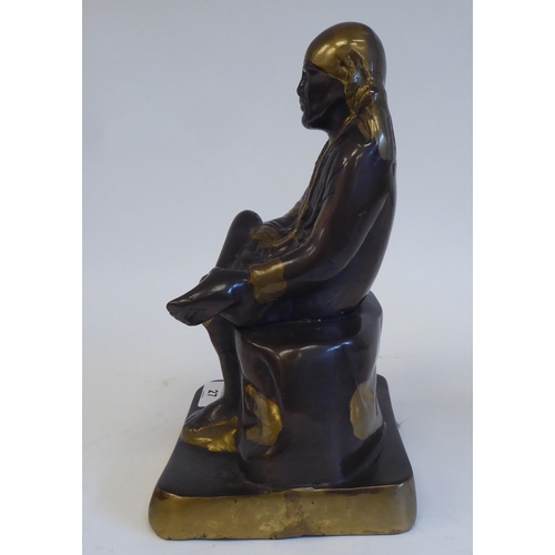 27 - A cast, patinated and part gilded bronze Asian figure, wearing traditional costume and seated on a r... 