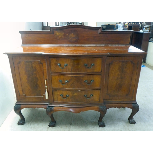 270 - A 1930s mahogany breakfront, bow fronted sideboard with a central bank of three drawers, flanked by ... 