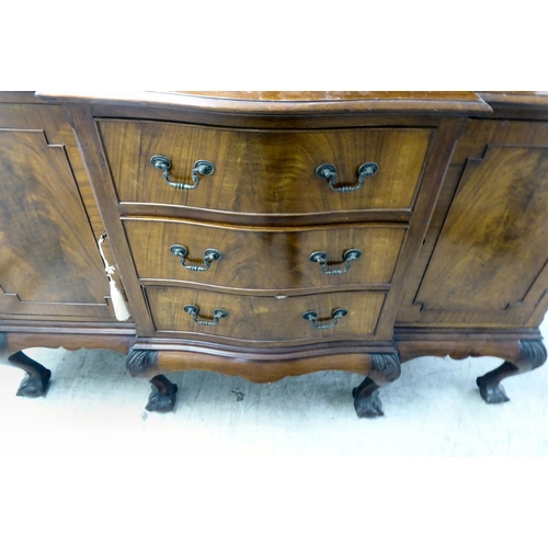 270 - A 1930s mahogany breakfront, bow fronted sideboard with a central bank of three drawers, flanked by ... 