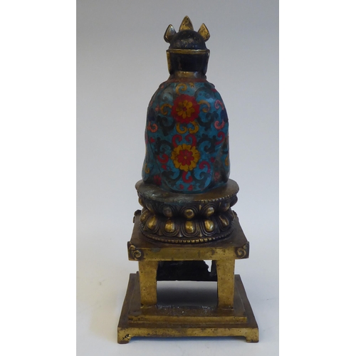 28 - An Asian cast brass and cloisonné Buddhist figure, seated cross-legged on a cushion plinth, g... 