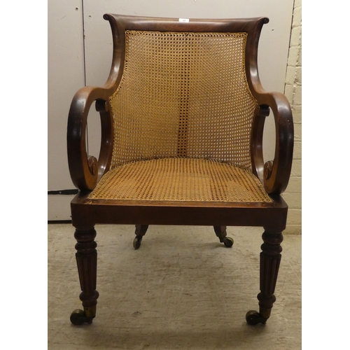 39 - A William IV mahogany framed bergere, the tub style back with a scrolled crest, a woven split cane b... 