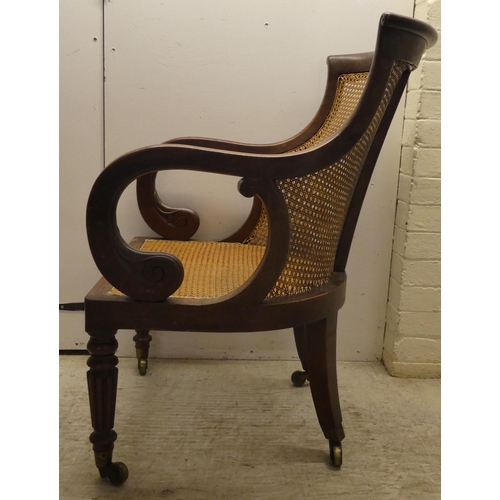 39 - A William IV mahogany framed bergere, the tub style back with a scrolled crest, a woven split cane b... 