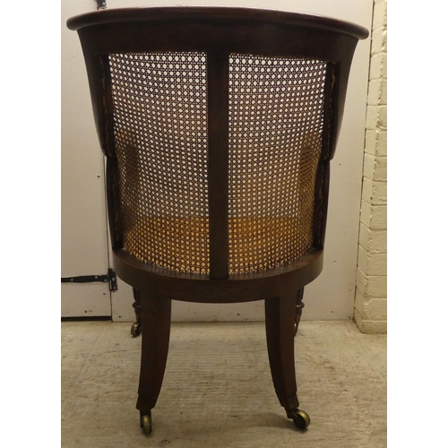 39 - A William IV mahogany framed bergere, the tub style back with a scrolled crest, a woven split cane b... 