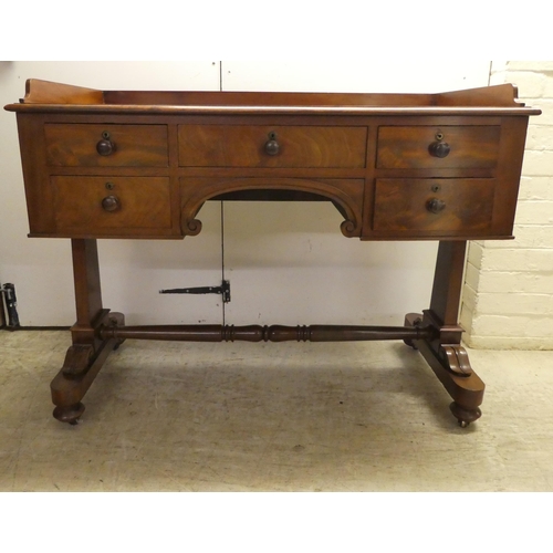 64 - A William IV mahogany desk, the top with a gallery over five drawers, raised on opposing pillar upri... 