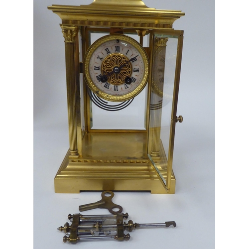 71 - An early 20thC gilt metal cased, four glass mantel clock with bevelled panels, surmounted by a twin ... 