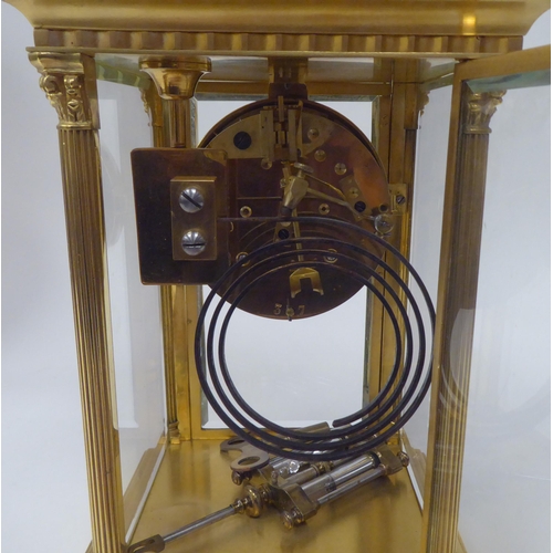 71 - An early 20thC gilt metal cased, four glass mantel clock with bevelled panels, surmounted by a twin ... 