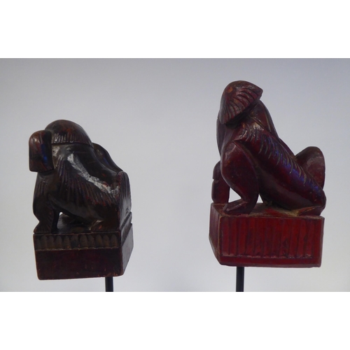 77 - A pair of 20thC Oriental, carved and stained ornaments, in the manner of Dogs of Fo, on a spiked ste... 