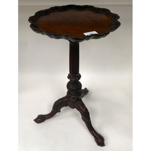 81 - A 19thC mahogany pedestal wine table with a piecrust border, over a fluted column and a profusely ca... 