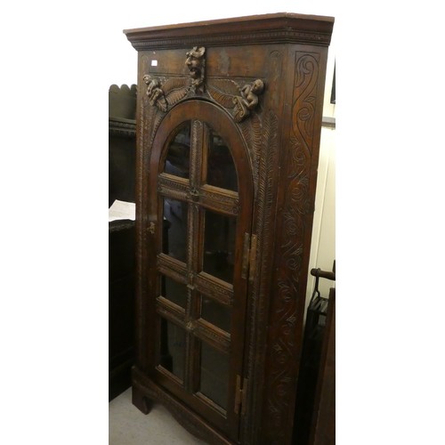 15 - A 19thC and later oak, standing corner cupboard with carved ornament, the full-height, multi-glazed ... 