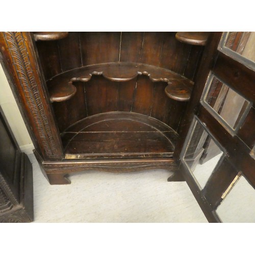 15 - A 19thC and later oak, standing corner cupboard with carved ornament, the full-height, multi-glazed ... 