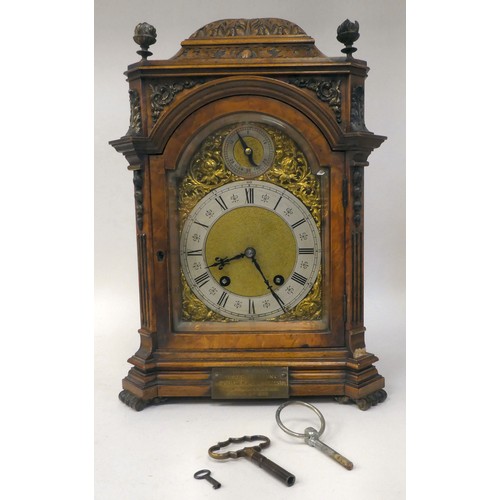 237 - A late 19thC burr walnut cased mantel clock with a domed top, brass finials, grilles and mounts; the... 