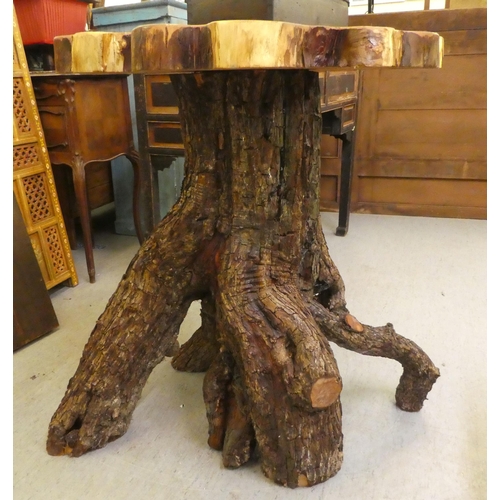 107 - A rough cut timber garden table, the crosscut, one piece top raised on a bark finished base  35