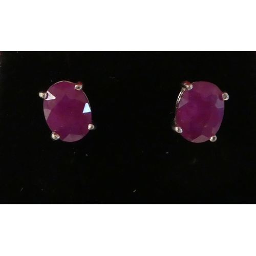 119 - A pair of claw set ruby earrings in white metal mounts 